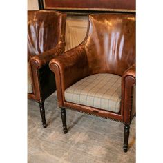 two brown leather chairs sitting next to each other