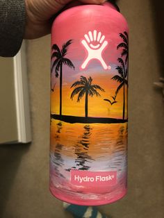 a hand holding up a pink water bottle with palm trees on it and the words hydro flask