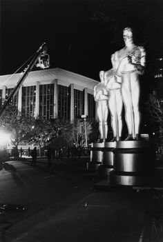 a black and white photo of a statue in front of a large building at night