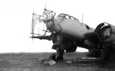 an old airplane sitting on top of a field next to a person kneeling in front of it