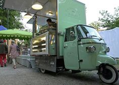 an ice cream truck is parked on the side of the road as people walk by