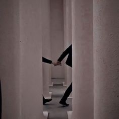 a woman in black and white is walking through an empty hallway with her arms stretched out