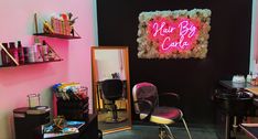 a hair salon with pink neon signs on the wall and chairs in front of it