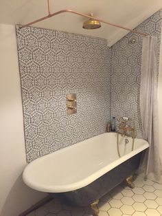 a bathroom with a bathtub, shower head and toilet paper roll on the wall