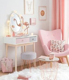 a room with pink furniture and pictures on the wall, including a vanity table and chair