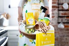 a woman holding a bowl with cleaning products in it