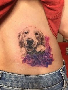 a woman's stomach with a dog and flowers tattoo on her side ribcage