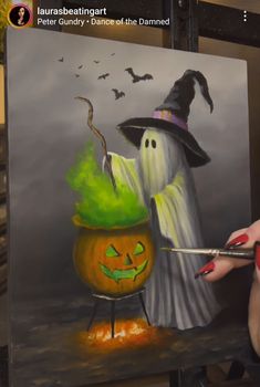 a woman is painting a halloween scene with pumpkins