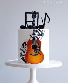 a white cake with an orange guitar and musical notes on the top, sitting on a pedestal