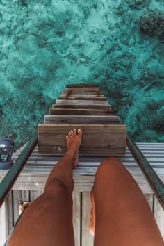 a person standing on a dock with their feet propped up against the railing and water in the background