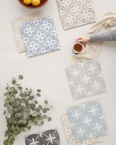 the table is covered with various tile designs and plants, including lemons, oranges, and a cup of coffee