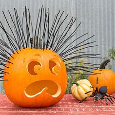 an orange pumpkin with spikes on it sitting next to two smaller pumpkins that have faces drawn on them