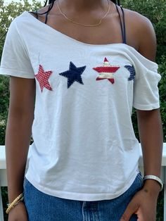 a woman wearing a white shirt with red, white and blue stars on the chest