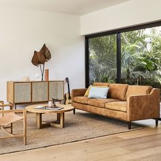 a living room filled with furniture next to a large glass window and wooden flooring