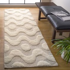 a large white rug with waves on it in front of a couch and chair next to a window