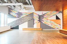 an empty room with wooden floors and colorful lines painted on the wall