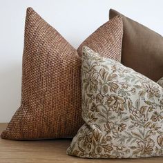 two brown and white pillows sitting on top of a wooden table next to each other