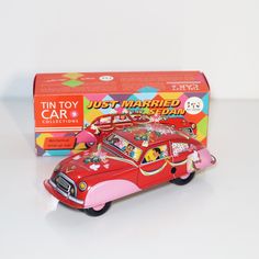 a red toy car sitting in front of a box