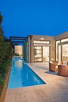 an outdoor living area with a pool and patio furniture at night, lit up by lights