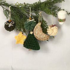 crocheted ornaments hanging from a tree branch on a white background with pine needles