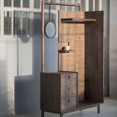 a wooden cabinet sitting next to a mirror on top of a wall near a window