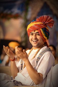 a man wearing a colorful headdress and holding his hands together