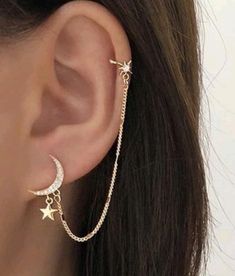 a woman wearing a gold chain ear cuff with stars and moon charms