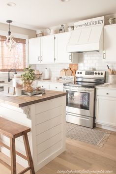 a kitchen with white cabinets and an island in front of a stove top oven next to a window