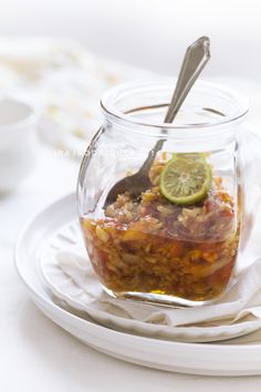 a glass jar filled with food sitting on top of a white plate next to a spoon