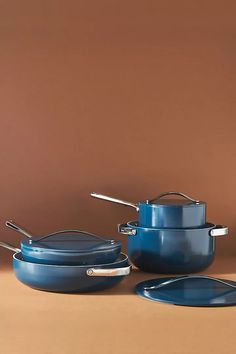 blue pots and pans are sitting on a brown surface with spoons in them