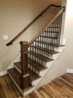 a wooden stair case next to a white wall