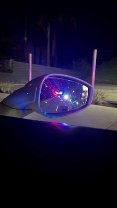 a car's rear view mirror with the lights on and its reflection in it