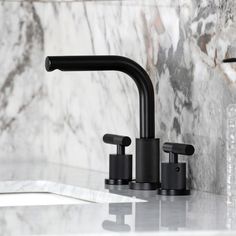 two black faucets sitting on top of a marble counter