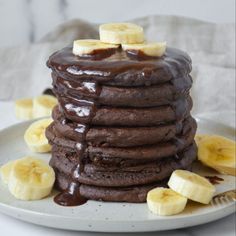 a stack of chocolate pancakes with bananas on top