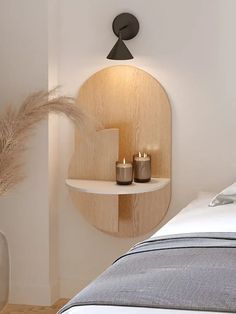 a bed with two candles on it next to a wall mounted shelf and vases