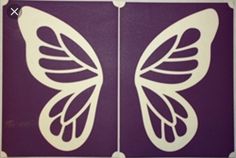 two white butterfly cut outs sitting on top of a purple wall