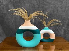 two vases sitting on top of a wooden table next to each other with plants in them