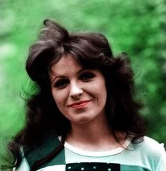 a woman with long hair wearing a green and white shirt