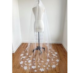 a mannequin wearing a veil with white flowers on the floor next to it