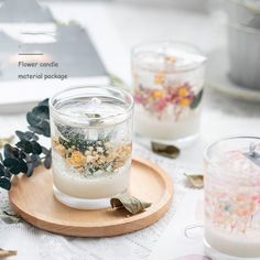 two glass jars filled with flowers sitting on top of a wooden tray next to candles