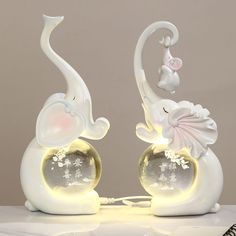 two white elephants are sitting on top of a table