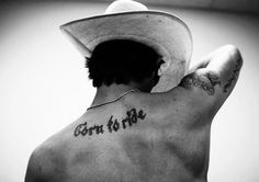 a man wearing a cowboy hat with the words born to me tattooed on his back