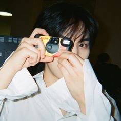 a young man holding two cell phones up to his face while looking through the lens