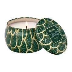 a candle that is inside of a green container with gold designs on the front and sides