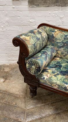 an ornately upholstered couch sits in front of a brick wall and floor