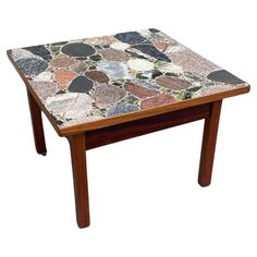 a small table with different colored stones on it's top and legs, against a white background