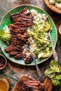 a green plate topped with steak, rice and lettuce next to bowls of salad