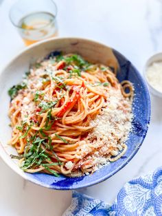 a blue bowl filled with pasta and parmesan cheese on top of a table