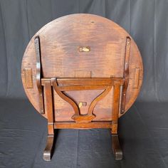 an old wooden table with two legs and a tray on one end, sitting against a black backdrop