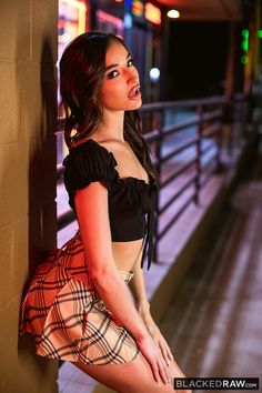 a beautiful young woman leaning against a wall